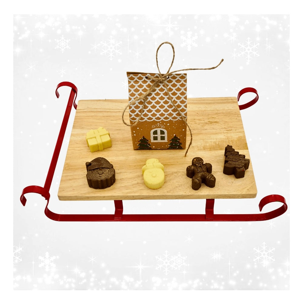 Christmas house with milk and white chocolate novelties displayed on a wooden sleigh