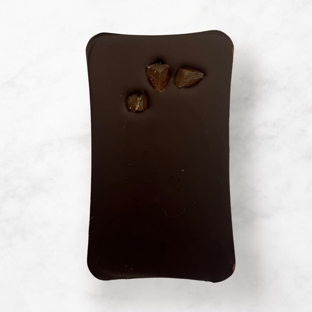 
                  
                    Dark chocolate bar with three Ginger pieces on a white background
                  
                