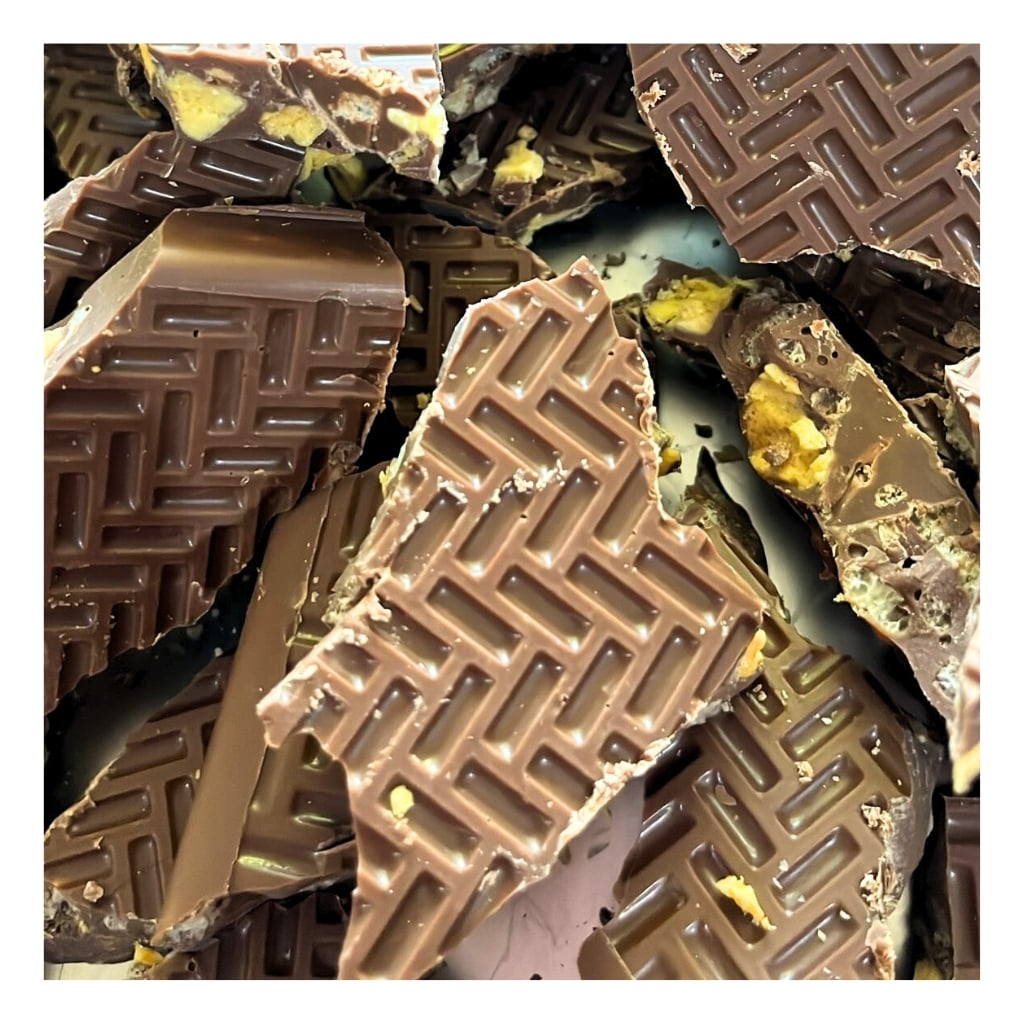 
                  
                    Close-up of  honeycomb krisp chocolate pieces with a distinctive pattern on a white background
                  
                
