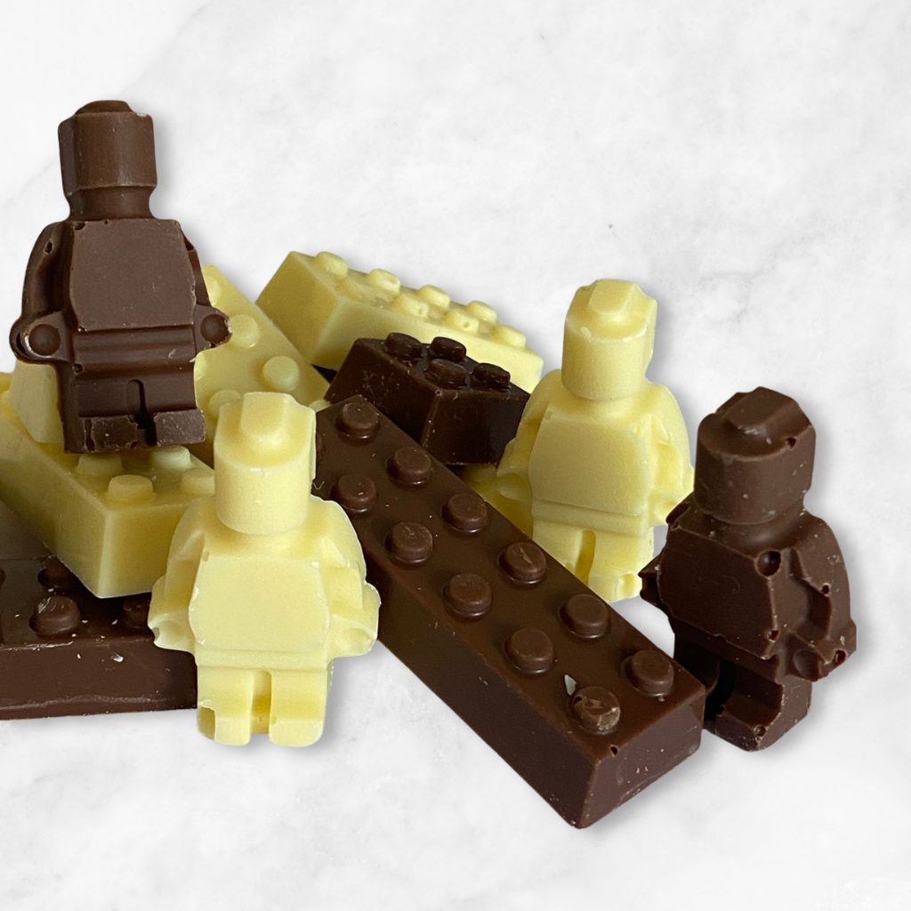 
                  
                    Chocolate sculptures of lego-like figures and bricks on a white background
                  
                