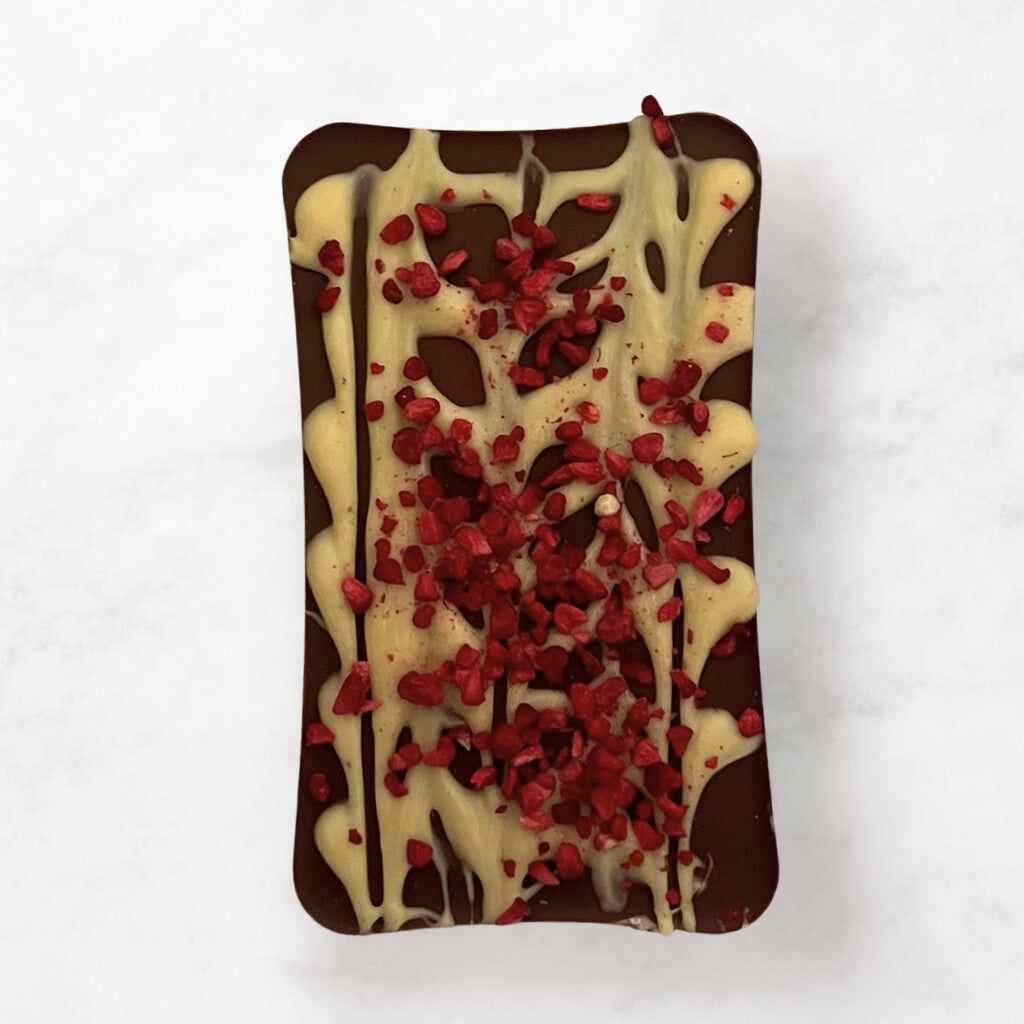 
                  
                    Milk chocolate bar with white chocolate drizzle and dried raspberry pieces on a white background
                  
                