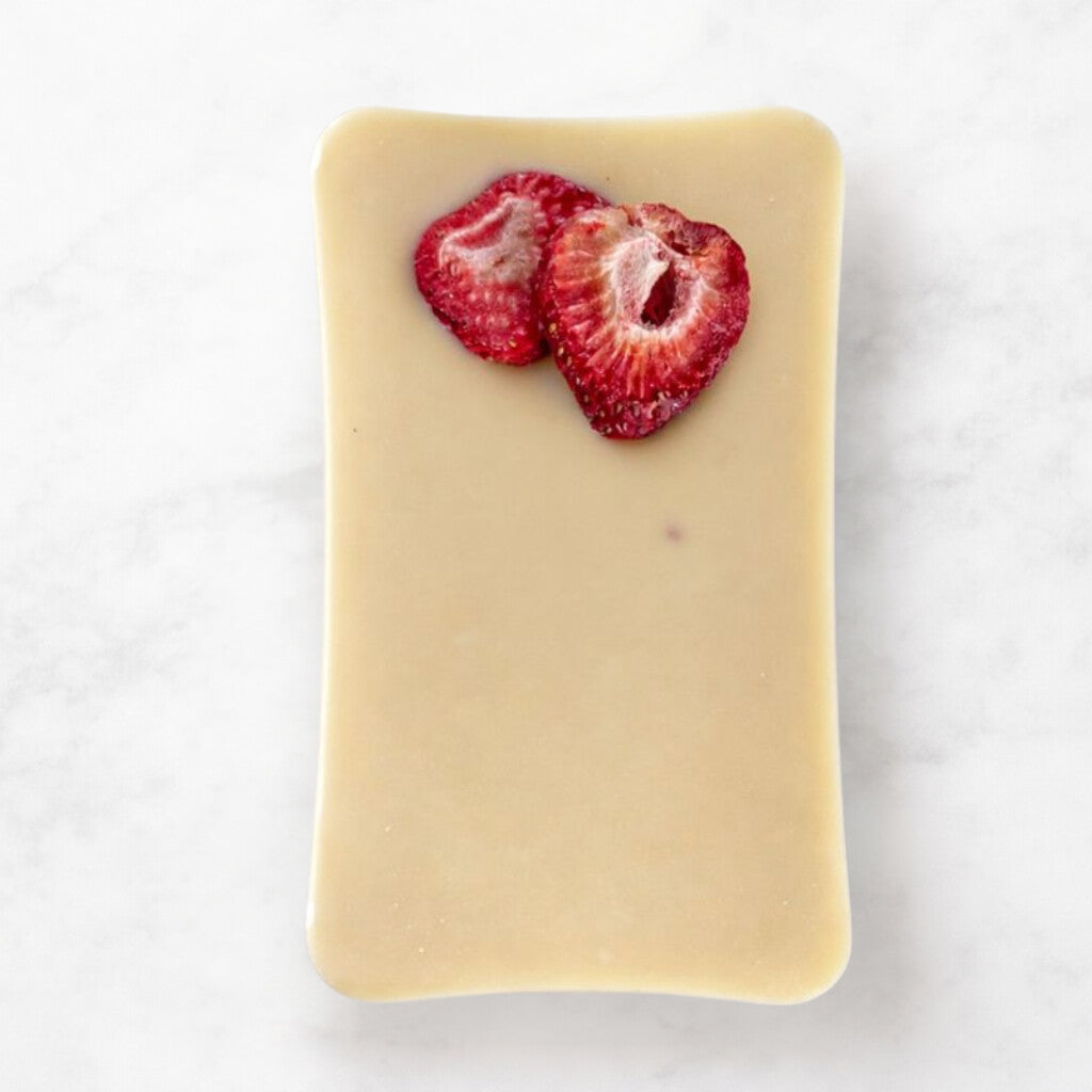 
                  
                    Bar of white chocolate with sliced strawberries on a white background
                  
                