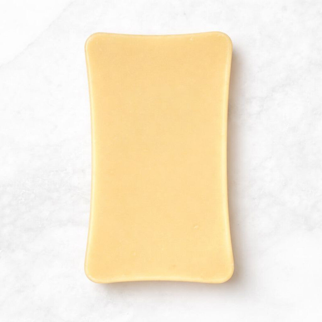 
                  
                    White chocolate bar from Sweet C's Chocolates on a light gray background with a wooden border.
                  
                